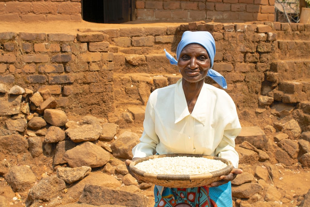 Rose Aufi shows some of her maize grain reserves. (Photo: Shiela Chikulo/CIMMYT)