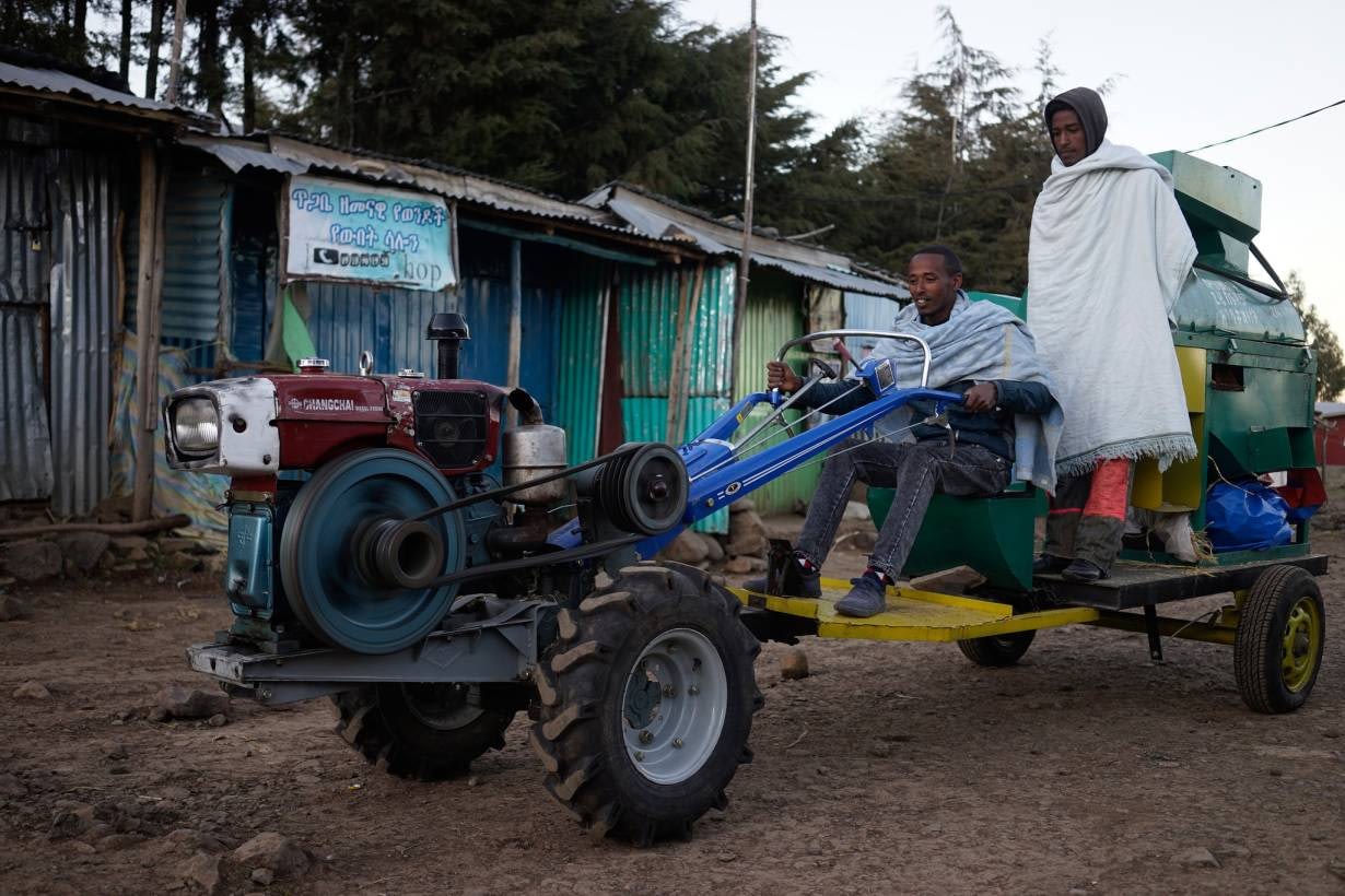 Service provider Bedilu Desta and his helper Fekadu Assefa drive a two-wheel tractor and thresher in the village of Gudoberet, Basona district, Ethiopia, in 2015. (Photo: Peter Lowe/CIMMYT)