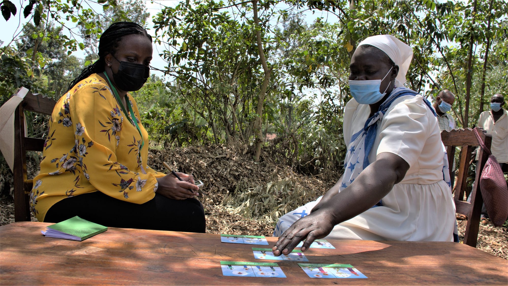 Pauline Muindi (left), Gender Research Associate at CIMMYT listens to Wilbroda (right), a maize farmer from Kakamega County, Kenya, giving feedback on decision-making between spouses on maize farming. On the table are vignettes showing five different decision-making scenarios based on fictitious husband and wife characters. (Photo: Susan Umazi Otieno/CIMMYT)